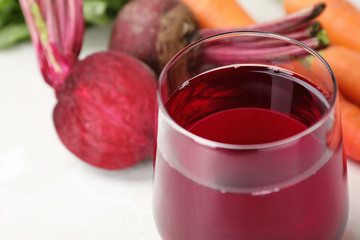 Glass with fresh beet juice on table, closeup