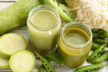 Jars with healthy baby food and ingredients on table