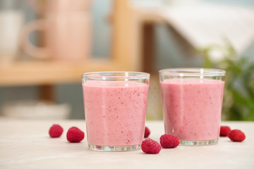 Delicious smoothie in glasses and raspberries  on table