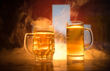 Creative concept. Beer glasses on table at dark toned foggy background with blurred view of flag of...