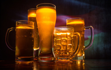 Creative concept. Beer glasses on table at dark toned foggy background with blurred view of flag of Germany.