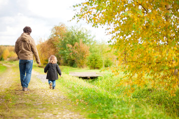 Father and daughter walking together, autumn day