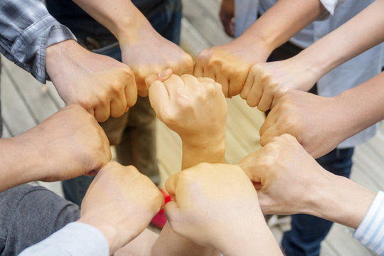 Image of young people putting their fists together by having a fist in the middle as symbol of unity and achievement, top view. Group of people fist bump assemble together. Concept teamwork