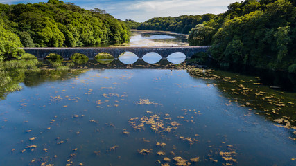 Fototapeta na wymiar Aerial drone view of an old bridge spanning a beautiful lake in a rural area of Wales