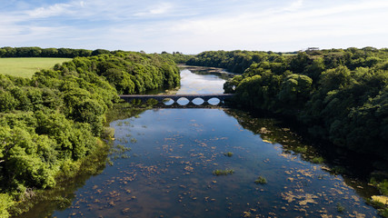 Fototapeta na wymiar Aerial drone view of an old bridge spanning a beautiful lake in a rural area of Wales