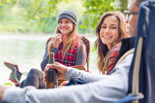 Young Adult Hispanic Girl with Bottle of Beer Enjoys Talking with Friends Outdoors