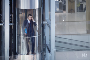 Businessman in modern glass elevator - Powered by Adobe