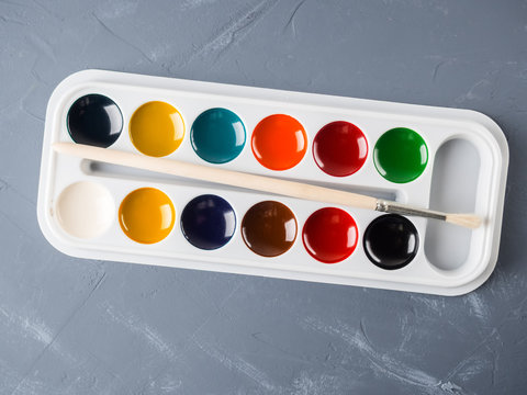 A set of children's watercolor paints and a brush