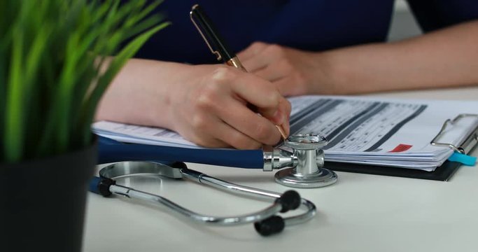 selective focus of flower in pot and Cropped image of stethoscope and doctor filling papers.