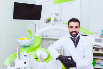 Closeup portrait of confident healthcare professional with arms folded standing next to white patient chair
