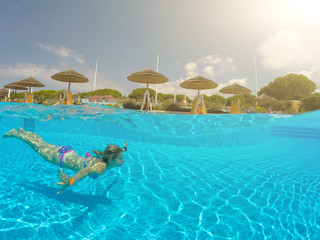 Fototapeta na wymiar Young woman swimming undewater in the swimming pool