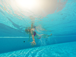 Young woman swimming undewater in the swimming pool