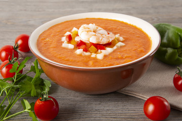 Soup gazpachos with shrimps, Italian cuisine. Plate with soup in a white plate on a rustic background.