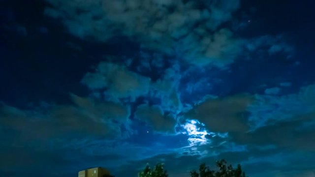 TIME LAPSE: dark sky with moving clouds, the full moon shining and moving clouds at night, timelapse with copy space. Holiday concept of Halloween night or holy Christmas night.