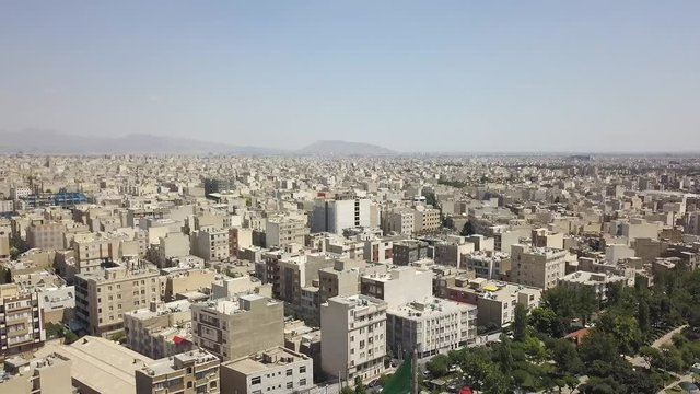 Aerial drone view of the houses next to the  Azadi tower in Tehran. Waving flag.  Iran 2018, may. A monument located at Azadi Square. 