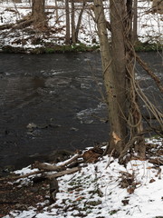 River in Winter - Flowing water in winter with snow on the banks.