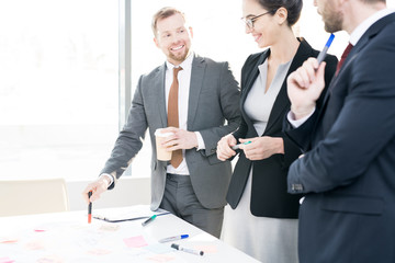 Portrait of successful business team standing at table and cheerfully collaborating on strategy project, copy space