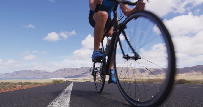 Professional cyclist riding racing bike in race competition on open road. Sports athlete man biking with high intensity on highway during summer cardio workout training. SLOW MOTION, RED EPIC.