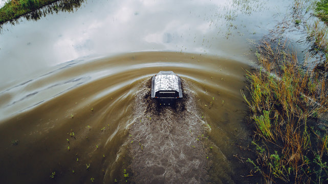 An Off-road Vehicle Sails On The River. Aerial Above View Top