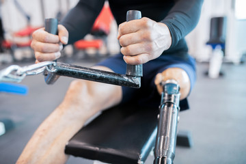 Mid section close up of unrecognizable muscular man with prosthetic leg using weight machines while working out  in gym, copy space - obrazy, fototapety, plakaty