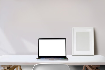Minimal workspace with blank screen laptop computer and mockup poster on studio desk.