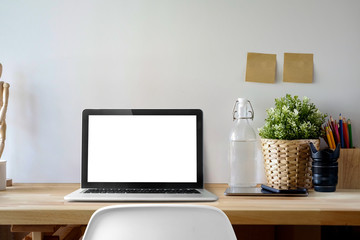 Contemporary workspace with mockup blank screen laptop on wooden desk.