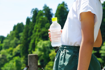 A woman holding a bottle of water.  ペットボトルの水を持つ女性