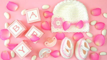 Baby girl nursery clothing and accessories overhead on blue wood table flat lay.