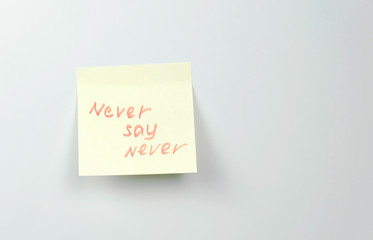 Note on yellow sticker paper sheets with motivation words never say never.