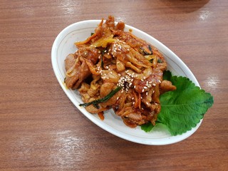 Korean food style, Top view of spicy stir fried pork  on white plate, Space for text in template, Jeyuk bokkeum is korea traditional on wooden table.