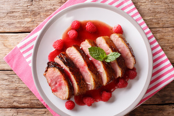 natural food: fried duck breast served with fresh raspberry sauce and mint closeup on a plate. horizontal top view