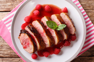 Delicious food sliced grilled duck breast with fresh raspberry sauce and mint closeup on a plate. horizontal top view
