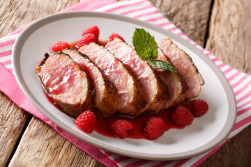 Delicious food sliced grilled duck breast with fresh raspberry sauce and mint closeup on a plate. horizontal
