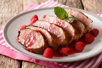 beautiful natural food: fried duck breast served with fresh raspberry sauce and mint closeup on a plate. horizontal