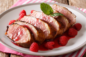 Delicious food gourmet: fried duck breast served with raspberry sauce and mint on a plate macro. horizontal