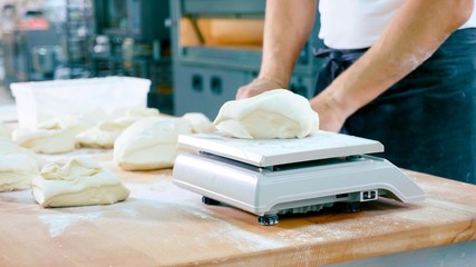 Professional baker divides the dough into portions and weights them