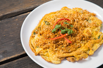Omelet (Omelette, Scrambled) with instant noodle on top on old wood table