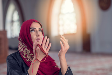 Fototapeta na wymiar Young muslim woman praying with rosary in mosque
