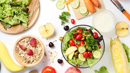 Top view of mixed vegetables salad, muesli and fresh fruits on white background.