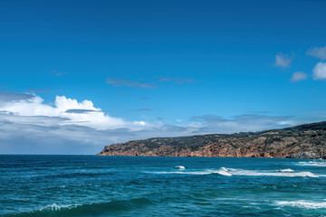 Waves are beating against rocky shore of sea on sunny summer day