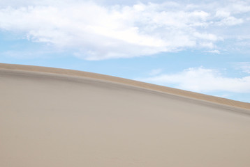 Sand dune and cloudy blue sky