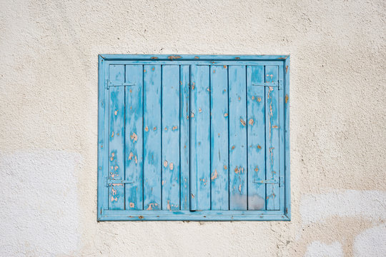 Cyprus, Larnaca. Blue wooden, peeled window, shutters on pink wall. Facade of building, closeup.