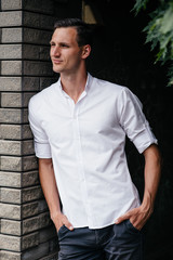 Portrait of a beautiful tall man in a white shirt on the street.