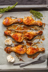 Grilled spicy chicken legs baked with garlic, rosemary and thyme on the pan.