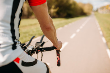 Male cyclist in sportswear cycling on asphalt road