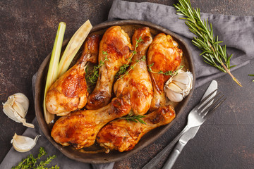 Grilled spicy chicken legs baked with garlic, rosemary and thyme on dark background.