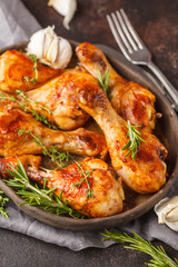Grilled spicy chicken legs baked with garlic, rosemary and thyme on dark background.