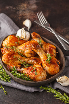 Grilled spicy chicken legs baked with garlic, rosemary and thyme on dark background.
