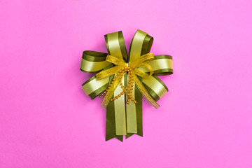 Decorative green ribbon bow on pink background, view from above with copy space for add text, template for festival or promotion and special day concept.