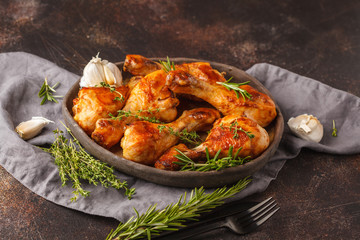 Grilled spicy chicken legs baked with garlic, rosemary and thyme on dark background.